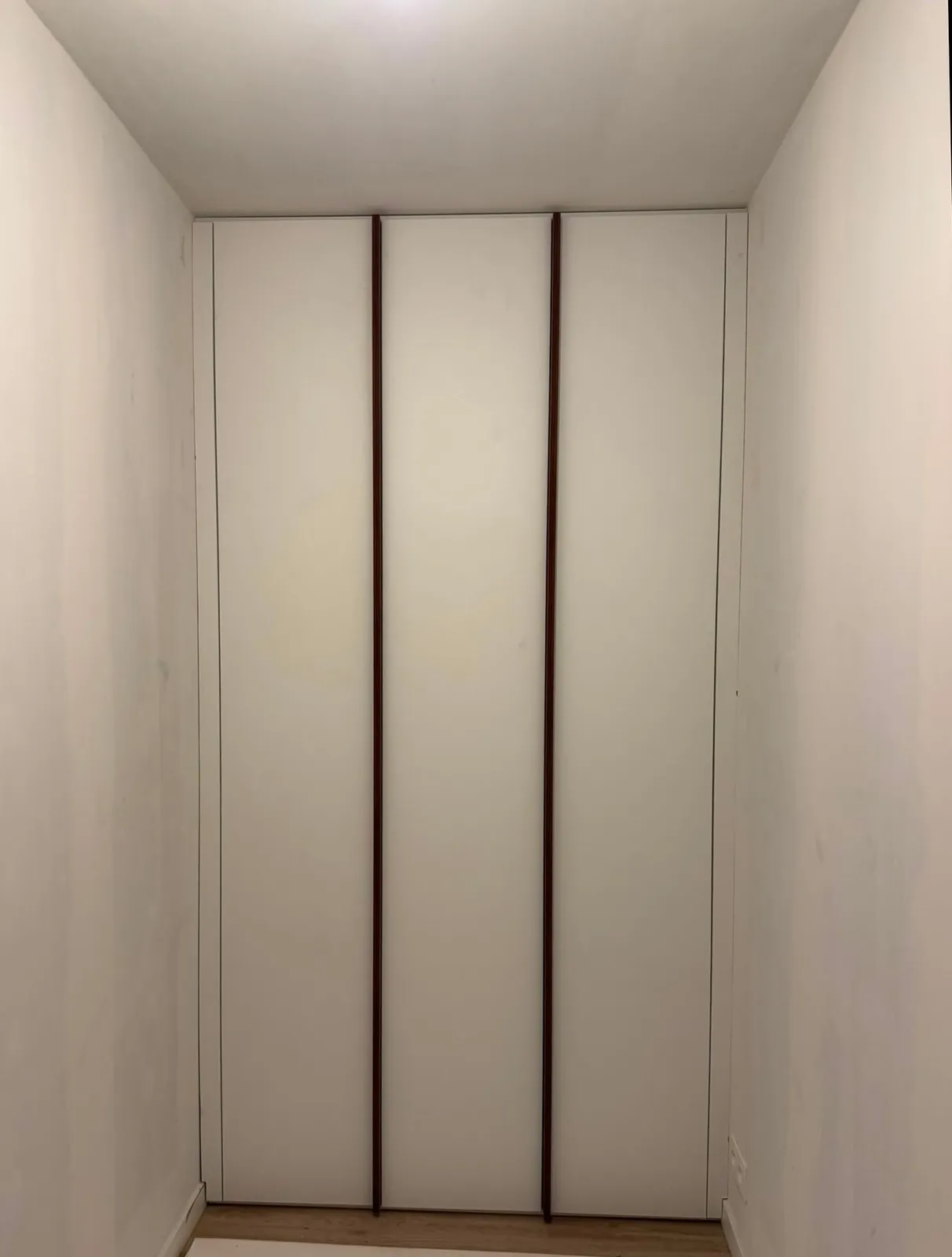 Witte inbouwkast op maat in de inkomhal met houten greeplijsten